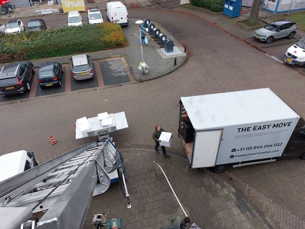 Verhuizer op het liftplatform op de 10e verdieping, een andere verhuizer verplaatst dozen in Amsterdam.